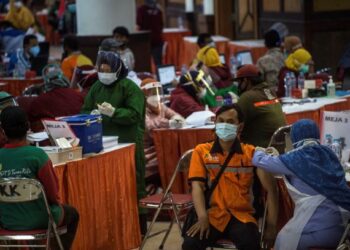 PETUGAS kesihatan melakukan suntikan vaksin kepada penduduk di Dewan Konvensyen, Surabaya. -AFP