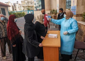 JURURAWAT memeriksa suhu penduduk Palestin yang tiba untuk menerima suntikan vaksin Covid-19 di Gaza City, Palestin. - AFP