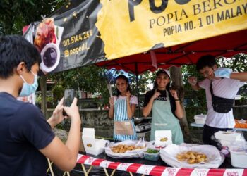 KELEBIHAN pelbagai aplikasi dimanfaatkan tiga beradik, Afiera Riana Agoes Riauwaldy, Afiefi Riani  dan Ahmad Amin untuk memuat naik kandungan  di media sosial sementara menunggu pelanggan di gerai mereka di Ampang, Selangor. – UTUSAN/MUHAMAD IQBAL ROSLI