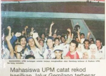 KERATAN akhbar Utusan Malaysia yang memperlihatkan kegembiraan para pelajar UPM selepas berjaya menghasilkan Jalur Gemilang gergasi pada 2001. – IHSAN PENULIS