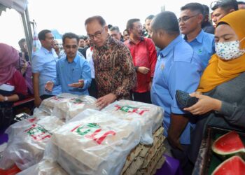 Anwar Ibrahim melihat barangan jualan selepas melancarkan Jualan Agro Rahmah di Tapak Bazar Ramadan Presint 3 di sini, hari ini. - UTUSAN/
FAISOL MUSTAFA