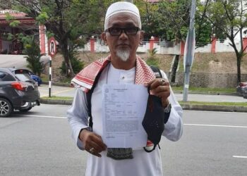 ROSLEI KAMISAN menunjukkan salinan laporan polis yang dibuatnya di Balai Polis Seremban 2, Seremban, hari ini. - UTUSAN/SYED AHMAD ZULKARNAIN SYED ALI