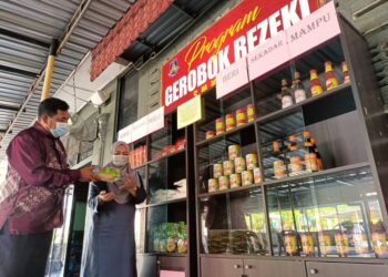 RAZAK Malek Taharim (kiri) dan Adura Mohamed menyusan barangan makanan ke dalam Gerobok Rezeki di Sekolah Menengah Kebangsaan (SMK) Kampong Pasir Puteh di Ipoh, Perak.