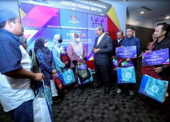 WAN Ahmad Dahlan Abdul Aziz berbual bersama penerima selepas menyerahkan sumbangan peralatan sekolah pada program i-Care4u di Bangunan Perdana Putra Putrajaya. - UTUSAN/FAISOL MUSTAFA