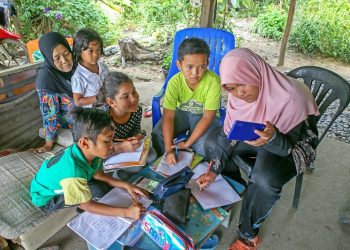 Salmah Ismail (kiri sekali) memerhatikan cucu-cucunya, Nur Suhaiza Sukri (kanan sekali) bersama Muhammad Irsyad Mat Asri  (dua dari kanan), Nurul Maslyani Ridzuan,  (tiga  dari kanan) dan Muhammad Ammar Muhsif, (empat dari kanan) berkongsi telefon pintar dan internet untuk sesi pembelajaran dalam talian di Kampung Padang Balai, Kuala Nerang, Kedah, baru-baru ini.   MINGGUAN/SHAHIR NOORDIN