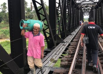 PENDUDUK Kampung Batu Enam, Kelantan menggunakan jambatan kereta api ke Bandar Gua Musang selepas jambatan konkrit runtuh, Julai lalu. - UTUSAN/AIMUNI TUAN LAH