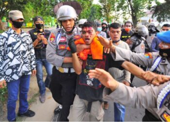 ANGGOTA polis menenangkan penunjuk perasaan yang cedera dalam insiden pergaduhan ketika demonstrasi bantah Cipta Kerja di Jambi, Indonesia. - ANTARA