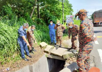 AZMI OSMAN (kiri) menunjukkan longkang tempat seorang lelaki terjatuh setelah motosikal ditunggangnya terbabas di Lebuh Persiaran Klebang 11, Chemor di Ipoh hari ini. - UTUSAN/ASLIZA MUSA