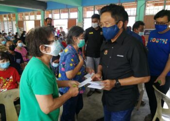 JALALUDDIN Alias menyampaikan BWI kepada penerima yang terjejas banjir di Sekolah Kebangsaan Dato’ Undang Abdullah, Kampung Chennah, Jelebu hari ini. - UTUSAN/ZAKKINA WATI AHMAD TARMIZI