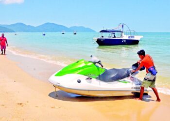 PEMBANTU pengusaha sukan air, Syahril Muzammil Toyyid mencuci jet ski ketika menunggu pengunjung
yang semakin berkurangan sejak penularan pandemik Covid-19 di Pantai Batu Ferringhi, Pulau Pinang,