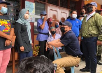 HISHAMMUDDIN Hussein (duduk, kanan) bersama Hasni Mohammad (kanan) ketika melawat keadaan mangsa banjir yang ditempatkan di PPS SK Tambang selepas rumah mereka di Kampung Spang Loi dinaiki air di Segamat, Johor. -UTUSAN/FARAHWAHIDA AHMAD