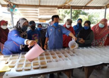 AHMAD Maslan menyediakan bubur manis untuk diedarkan kepada orang ramai anjuran Pusat Daerah Mengundi Parit Keroma di Kampung Parit Haji Ahmad di Pontian, di sini.