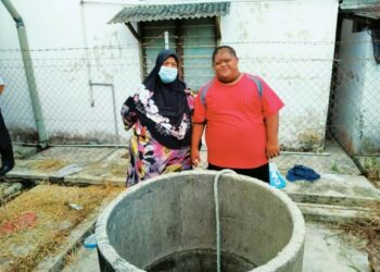 RAHMAH Zeyrab Khan (kiri) bersama salah seorang anaknya di telaga yang digunakan mereka sekeluarga selama empat tahun di rumahnya di Pekan Nanas, Pontian, Johor. – FOTO/MUHAMMAD ZIKRI