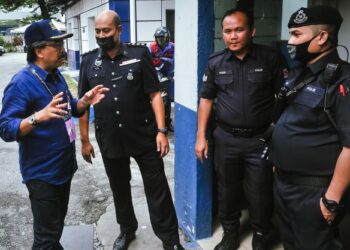 JOHARI Abdul Ghani (kiri) berbual dengan anggota polis semasa melawat pusat pengundian awal di Balai Polis Jalan Tun Razak, Kuala Lumpur, semalam. - UTUSAN/M. FIRDAUS M. JOHARI