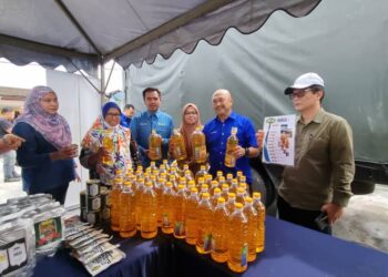 ABD. Rahman Bakri (tengah) menunjukkan barangan yang dijual pada program itu di Kampung Nelayan, Sungai Besar, Sabak Bernam, Selangor. -UTUSAN/ ISKANDAR SHAH MOHAMED