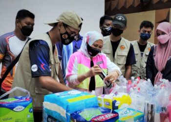 WASITAH Mohd. Yusof (tengah) membantu menyusun barangan keperluan mangsa banjir ketika melawat pusat pengumpulan barangan keperluan pasca banjir di Kompleks Belia dan Sukan di Paroi, Seremban, Negeri Sembilan,  hari ini. - UTUSAN/BADRUL HAFIZAN MAT ISA