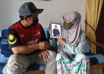 RUFISHAH Zakarya bersama Muhammad Firdaus Mohd. Faisol menunjukkan gambar Muhammad Shahrizal Mohd. Faisol di Taman Keladi, Sungai Petani, Kedah, semalam. - FOTO/OTHMAN YAHAYA