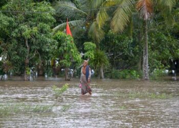 SEORANG penduduk meredah air banjir di Kampung Alor Tebuan, Mukim Tajar, Alor Setar, Kedah. - FOTO/SHAHIR NOORDIN