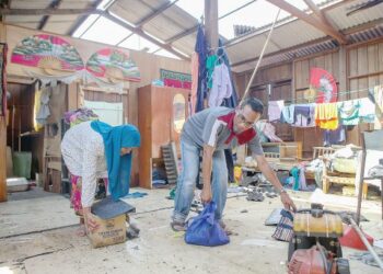 SHAHNUM Ahmad dan Murni Hassan mengemas barangan yang basah setelah bumbung rumah mereka mengalami kerosakan dalam kejadian ribut di Felda Lubuk Merbau, Padang Terap, Kedah. - UTUSAN/ SHAHIR NOORDIN