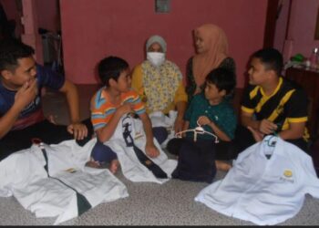 MUHD. Afiq Ikhwan Muhd. Saifol (kiri) bersama tiga adiknya menunjukkan pakaian sekolah mereka sambil diperhatikan Che Gayah Hamzah (belakang, kiri) dan Siti Farahana Omar (belakang, kanan) di Kampung Teluk Nipah Pantai Merdeka, Kota Kuala Muda, Sungai Petani, Kedah, semalam. – MINGGUAN/OTHMAN YAHAYA