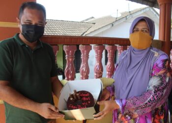 SUHAIMIZAN bIZAR menyampaikan kek tertera tulisan Selamat Hari Guru Cikgu Tipah kepada Latifah Ab. Samad sempena sambutan Hari Guru. -UTUSAN/NOR AINNA HAMZAH