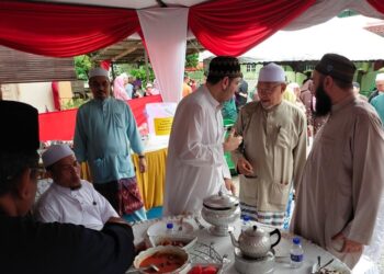 AHMAD Yakob (dua kanan) meraikan tetamu di rumah terbuka di Kampung Alor Pasir, Tumpat hari ini. - UTUSAN/YATIMIN ABDULLAH