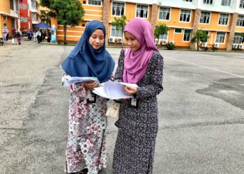 NUR A’lya Nadhirah Razali (kiri) bersama Nur A’naa Sakinah melihat borang permohonan kemasukan ke UMK Kampus Kota, Pengkalan Chepa, Kelantan. - UTUSAN/ROSLIZA MOHAMED