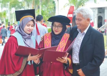 MOHD. Shakri Yaacob melihat PhD dan ijazah sarjana yang diterima Masrina Akmal Salleh (tengah) dan Nur Aiman Amini dalam Konvokesyen UTM ke-65 di UTM Skudai, Johor. - UTUSAN/RAJA JAAFAR ALI