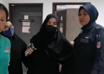 ANGGOTA polis (kanan) mengiringi kedua-dua tertuduh semasa menghadiri perbicaraan di Mahkamah Majistret Kota Bharu, Kelantan hari ini-UTUSAN/ROSALWANI CHE SOH