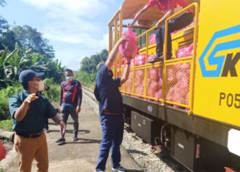 PETUGAS misi bantuan memindahkan barangan ke dalam troli rel untuk dihantar segera kepada mangsa tiga perkampungan di Gua Musang, Kelantan. – IHSAN KTMB