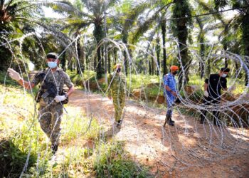 ANGGOTA polis, tentera, APM dan Rela bersama memeriksa kawat duri yang dipasang di salah satu laluan masuk Kampung Lakai , Jelebu, Negeri Sembilan yang dikenakan PKPD bermula hari ini sehingga 27 Jun ini. - UTUSAN/MOHD. SHAHJEHAN MAAMIN