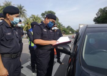 SHAFIEN Mamat (kanan) memeriksa dokumen pemandu yang mahu merentas negeri ke Terengganu di SJR Bukit Yong, Pasir Puteh hari ini. - UTUSAN/TOREK SULONG