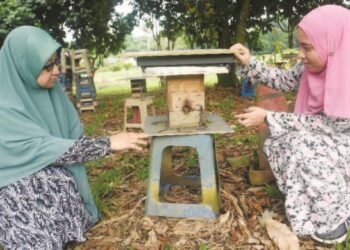 DR. NORHASNIDA Zawawi (kiri) melihat sarang lebah kelulut di Ladang 10, UPM, Serdang, Selangor. – IHSAN UPM