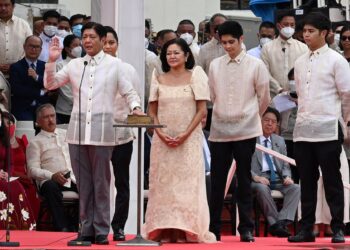 MARCOS JR. mengangkat sumpah sebagai Presiden Filipina baharu di samping isteri dan anaknya di Muzium Negara, Manila, semalam.-AFP