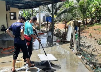 DUA sukarelawan sedang melakukan kerja-kerja pembersihan selepas air banjir mula surut di Masjid al-Wakil, Lubok China, Melaka. - UTUSAN/AMRAN MULUP