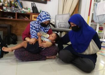 AQEEL Zayaan Mohd. Zuki yang bakal berusia genap dua tahun pada 17 Julai ini dipangku ibu saudaranya, Nuraishah Ali Khan sambil diperhatikan kakaknya Damia Irdina ketika ditemui di kediamannya di Al Muktafi Billah Shah (AMBS) di Dungun hari ini. -UTUSAN/NIK NUR IZZATUL HAZWANI NIK ADNAN