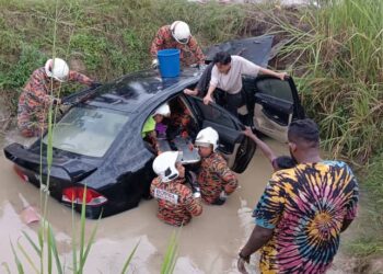 ANGGOTA bomba mengeluarkan mangsa dalam kereta yang terbabas dalam parit di Jalan Chui Chak-Langkap di Teluk Intan hari ini. - UTUSAN/JBPM PERAK