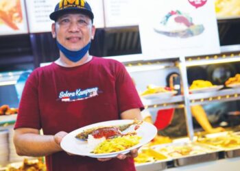 SEORANG pekerja restoran menunjukkan hidangan menu Rahmah berharga RM5 yang dilancarkan di Mydin Subang Jaya, baru-baru ini.