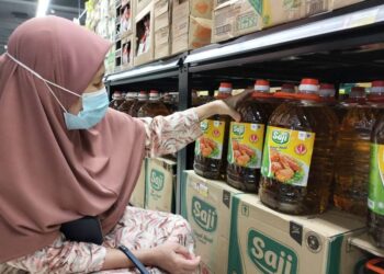 ANISAH Abdul Hamid melihat harga baru minyak masak sawit tulen botol yang dijual dengan harga RM34.70 di sebuah pasaraya di Kota Bharu, Kelantan, semalam. - UTUSAN/ ROHANA ISMAIL