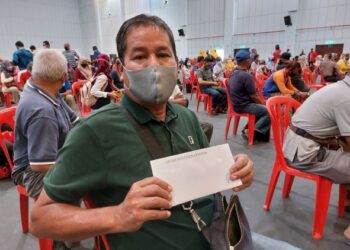 ISHAK Mohd. Din menunjukkan sampul bantuan tunai RM1,000 diterimanya pada Program Penyampaian Sumbangan Wang Ihsan NADMA Daerah Melaka Tengah, Melaka. - FOTO/DIYANATUL ATIQAH ZAKARYA