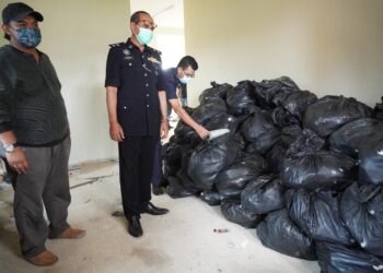 NANDA MAAROF (tengah) melihat kira-kira satu tan metrik daun ketum bernilai lebih RM50,000 dan tiga gram dadah jenis methamphetamine yang dirampas dalam operasi di sebuah rumah kosong di Kampung Guar Sanji, Arau, Perlis hari ini.- UTUSAN/NAZLINA NADZARI