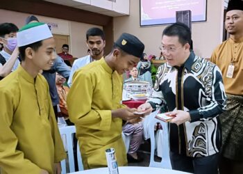 NGA Kor Ming (kanan) menyampaikan sumbangan duit raya kepada anak yatim pada Majlis Rumah Terbuka Hari Raya Aidilfitri Parlimen Teluk Intan di Teluk Intan hari ini. - UTUSAN/ZULFACHRI ZULKIFLI.