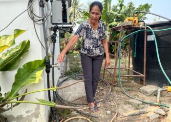 SEORANG penduduk, Cham Eng membuka pili bagi menunjukkan tekanan air di rumahnya di Kampung Kubang Tiga, Padang Besar, Perlis, semalam. – UTUSAN/ASYRAF MUHAMMAD