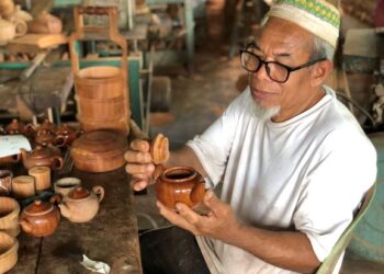 TAJUDDIN Husin menunjukkan teko kayu yang dikilat untuk dipasarkan di bengkelnya di Kampung Pokok Machang, Kuala Nerang, Padang Terap, Kedah baru-baru ini. -UTUSAN/JAMLIAH ABDULLAH