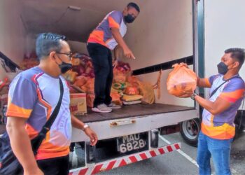 MOHD. Shahril Anuar (kanan) bersama rakannya membawa masuk barangan keperluan ke dalam lori untuk diagihkan kepada mangsa-mangsa terjejas banjir di beberapa kawasan. - UTUSAN/BADRUL HAFIZAN MAT ISA