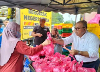 MOHD. Zolkafly Harun (kanan) membantu gerai jualan ayam pada 'happy hour' di Pasar Tani Mesra sempena Hari Bertemu Pelanggan di pekarangan Stadium Indera Mulia, Ipoh hari ini. - UTUSAN