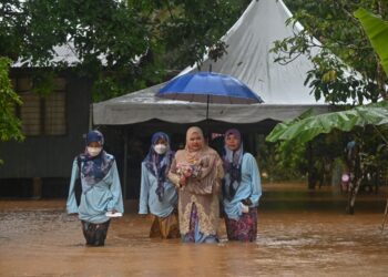 ZALEHA Ahmad ditemani keluarganya meredah banjir di pekarangan rumah untuk ke majlis pernikahan di Kampung Matang di Hulu Terengganu hari ini. - UTUSAN/PUQTRA HAIRRY ROSLI