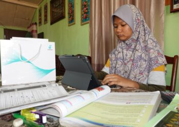 PELAJAR tingkatan tiga, Fatin Fatihah Fadzillah yang merupakan salah seorang penerima peranti digital Yayasan Petronas menyertai sesi PdPR di rumahnya di Kota Tinggi, Johor.