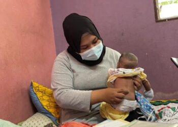 CHE Mastura Che Abdullah menunjukkan bayinya yang dilahirkan tiada tulang punggung di rumahnya di Felda Jengka 14, Maran, Pahang. - UTUSAN/SALEHUDIN MAT RASAD