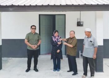 SITI Norizan Hasan (dua dari kiri) menerima kunci RRP daripada Mustapa Long di depan rumahnya di Kampung Bapong di Lipis, Pahang. – FOTO/HARIS FADILAH AHMAD